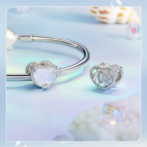 Macro detail of silver heart bead charm with iridescent stone and shell decoration