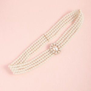 Detail of multi-layer white pearl waist chain with gold rhinestone buckle and floral accent