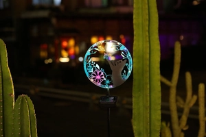 Solar yard light detail featuring glowing cat and butterfly silhouette in blue light