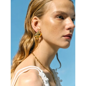 Golden sea shell earrings and matching necklace set for women under a clear blue sky