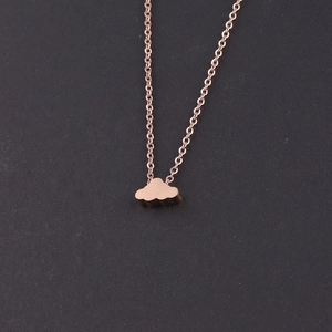 Close-up of a rose gold cloud-shaped pendant on a chain necklace over black background