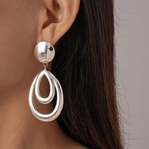 Close-up of model wearing silver double teardrop metal earrings with a polished finish