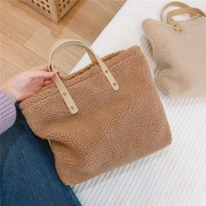 Close-up of caramel fleece handbag with leather handles and metal rivet details