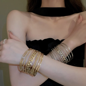 Detail shot of multilayered gold and silver geometric bracelets with textured metal finish