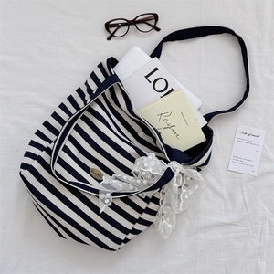 Flat lay of striped canvas tote bag with lace bow decoration and stylish lifestyle props