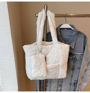 Detail view of white quilted tote bag featuring floral stitching and small coin purse