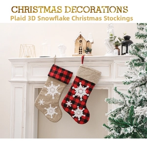 Detail of red plaid and burlap Christmas stockings with 3D snowflake on a white fireplace
