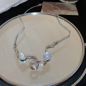Detailed view of silver snake chain necklace with dual iridescent faux cat eye pendants