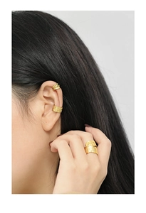 Macro shot of gold-plated irregular textured ear cuffs and matching ring on model