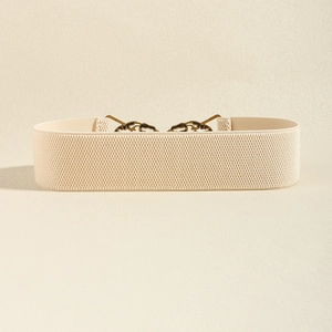 Detail of beige elastic waist belt featuring vintage bronze crane leaf metal buckle