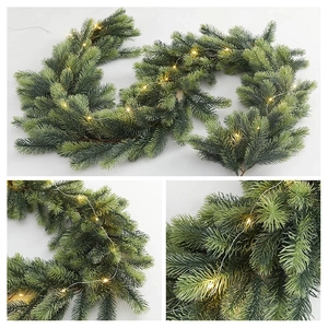 Macro shot of high-density PE artificial pine garland with warm white LED string lights