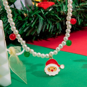 Detail of Christmas snowman pearl necklace with red and green beads on festive background