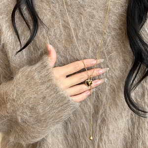 Gold Y-shaped necklace with a brown resin heart pendant on a cozy mohair sweater