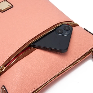 Close-up of pink pebble grain leather bag featuring dual golden metal zippers and storage pocket