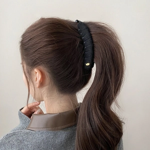 Close-up of black velvet flocking hair clip with fine golden metallic oval detail