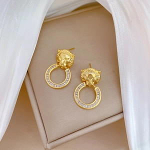 Detail view of lion head earrings with gold plating and sparkling zircon circle drop