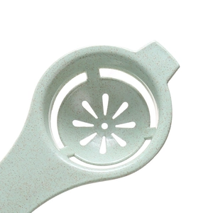 Light green wheat straw egg white separator tool with long handle on white background