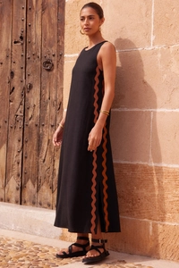 Detail of elegant black sleeveless midi dress with brown wave trim and side slit design
