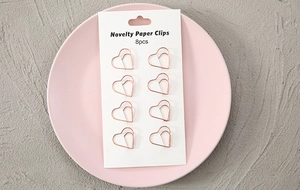 Macro detail of 8 rose gold heart-shaped paper clips on a novelty white product card