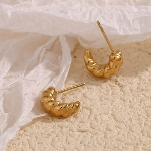 Detailed view of gold twisted croissant earrings with 18K gold plated texture on paper