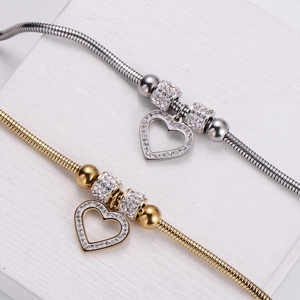 Silver and gold stainless steel snake bone bracelets with pavé heart charms on display