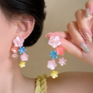Boucles d'oreilles fleuries à pampilles avec fleurs en résine pastel portées par mannequin