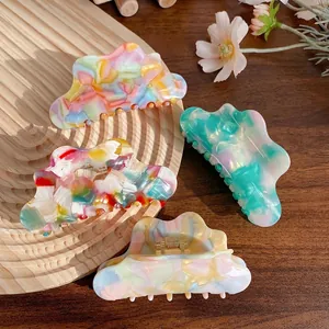 Cloud shaped acetate hair claws in colorful marble patterns on a wooden tray