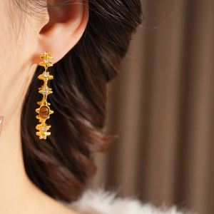 Detailed close-up of vintage gold earrings with tiger eye stone and white zircons
