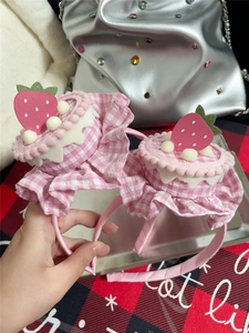 Detail of pink plaid strawberry cake hair clips with white pom poms and cute fabric decor