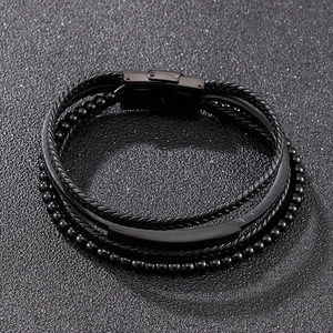 Macro view of men's multilayered black leather braided bracelet with metal clasp