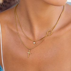 Detail of double-layer gold snake chain featuring a cross and zircon stone pendant