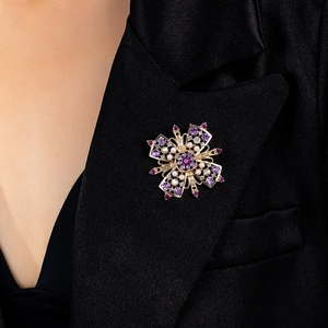 Vintage Blumenbrosche in Gold mit lila Kristallen und Perlen am schwarzen Revers
