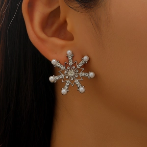 Detailed close-up of a snowflake earring with white pearls and sparkling crystals on model