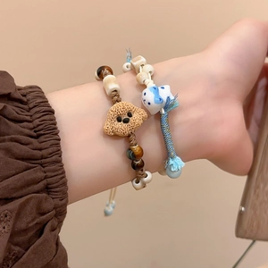 Detail of handmade ceramic beaded bracelets featuring cute cat and puppy pendants on wrist