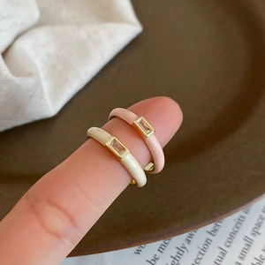 Close-up of gold rings with cream and pink enamel and square cubic zirconia stones