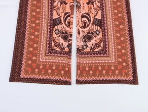 Detailed close-up of paisley print on bohemian red-brown wide leg trousers hem