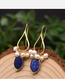 Detailed craftsmanship of vintage lapis lazuli earrings with natural pearls on wood