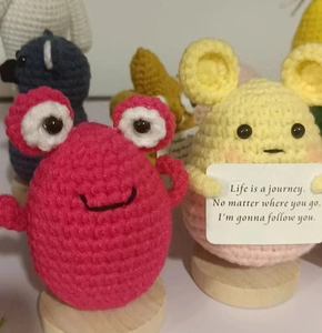 Detailed close-up of handmade crochet dolls with motivational message cards on wood bases
