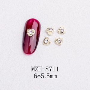 Close-up of heart nail charm MZH-8711 with gold rim and clear crystal on red nail art
