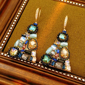 Close-up of vintage gold triangle earrings with multi-colored crystals on brown fabric