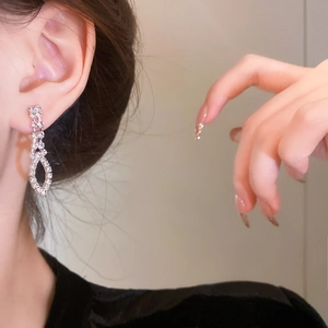 Close-up of sparkling hollow rhombus fringe earrings with crystals on a female model