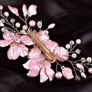 Detail of pink floral hair clip with pearls and crystals on black satin fabric