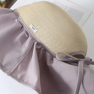 Dettaglio cappello di paglia con tesa in tessuto arricciato lilla e fiocco decorativo