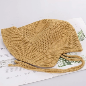 Detail of khaki crochet sun hat featuring hollow knit pattern and woven chin straps
