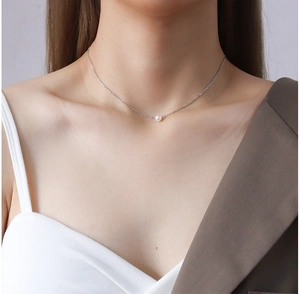 Close-up of a delicate silver chain necklace featuring a small white pearl pendant