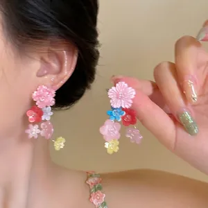 Détail de boucles d'oreilles fleurs colorées en résine portées par un mannequin