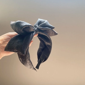 Detailed view of the textured black seersucker oversized bow headband for women