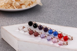 Close-up of faceted crystal ball earrings in multiple colors with golden hooks