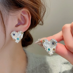 Macro view of silver heart earrings with liquid metal texture and colorful rhinestones