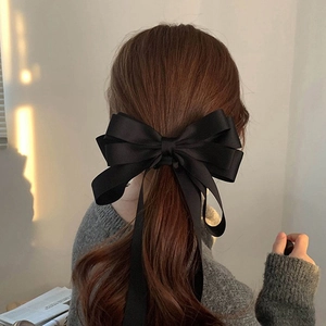Elegant large black satin bow hair clip with long ribbons on a ponytail